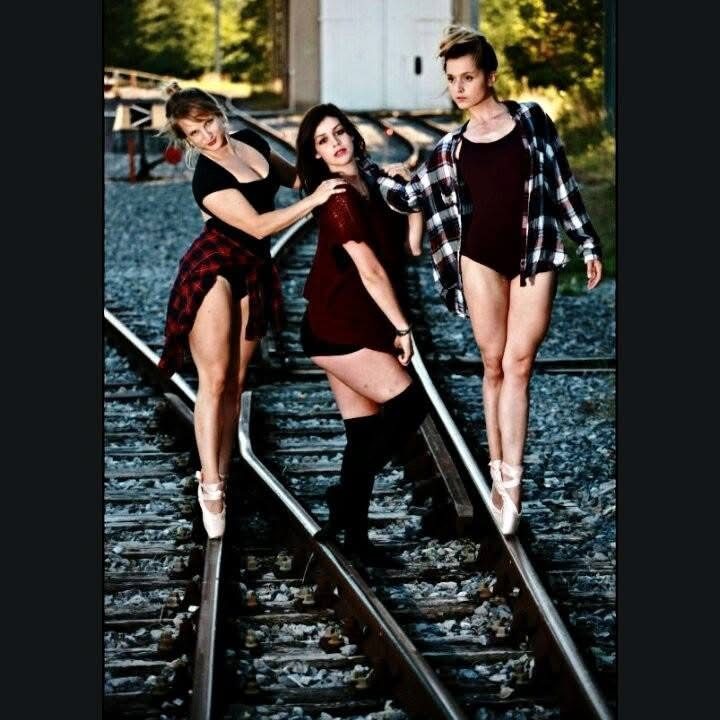 Three women posing together on train tracks